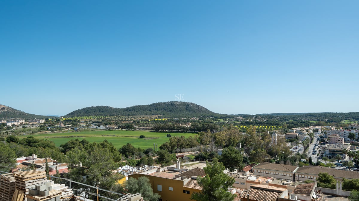 Vue surélevée d'un village méditerranéen, de vallées et de collines sous un ciel bleu clair depuis un chantier.