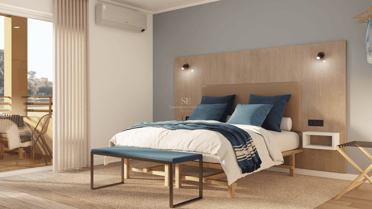 Chambre lumineuse avec lit double, tête de lit en bois et accès à un balcon ensoleillé.