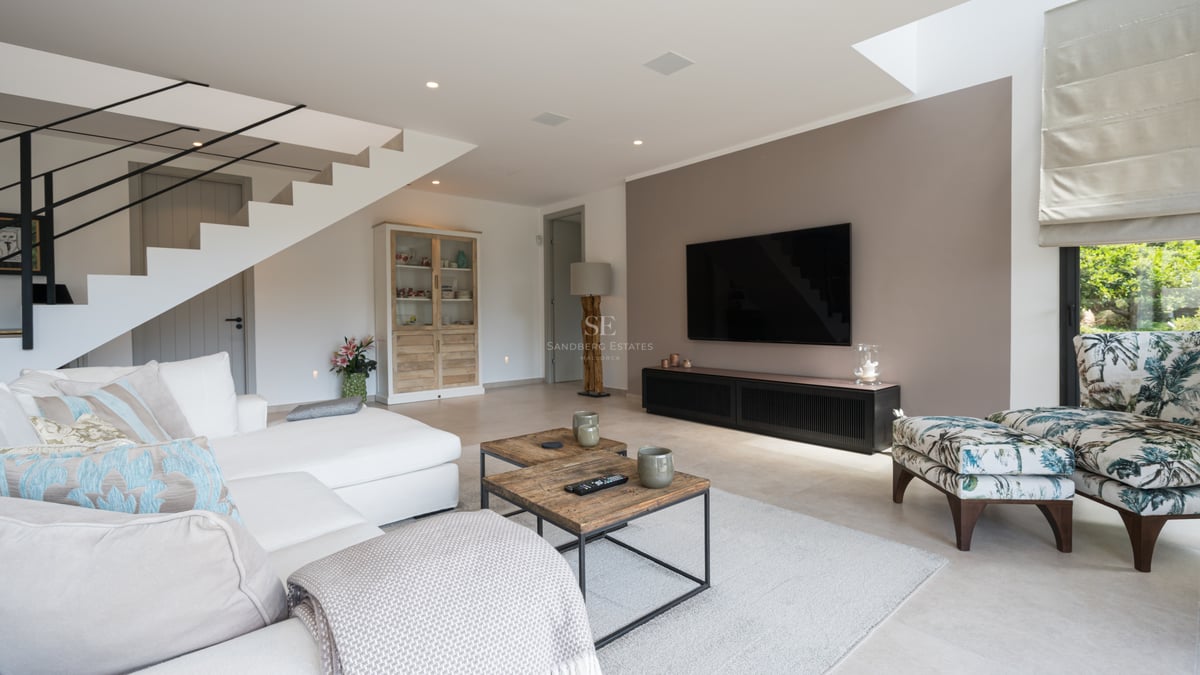 Salon spacieux et lumineux avec de grandes baies vitrées et accès à un balcon offrant une vue panoramique sur la mer. Mobilier moderne dans des tons neutres.