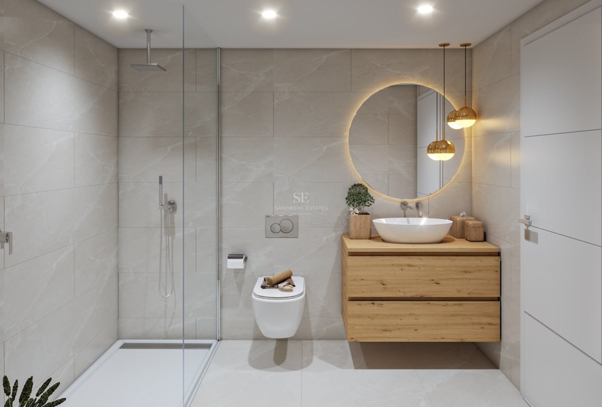 Contemporary bathroom featuring a glass walk-in shower, wooden vanity, round backlit mirror, and beige stone tiles.