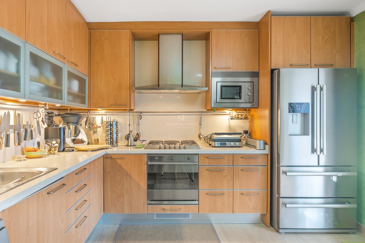 Zeitgenössische Küche mit hellen Holzschränken, Edelstahlgeräten und integrierter Unterbaubeleuchtung.