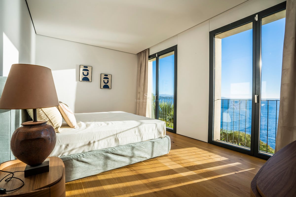 Modernes Schlafzimmer mit Eichenparkett, bodentiefen Fenstern und Blick auf das azurblaue Mittelmeer.
