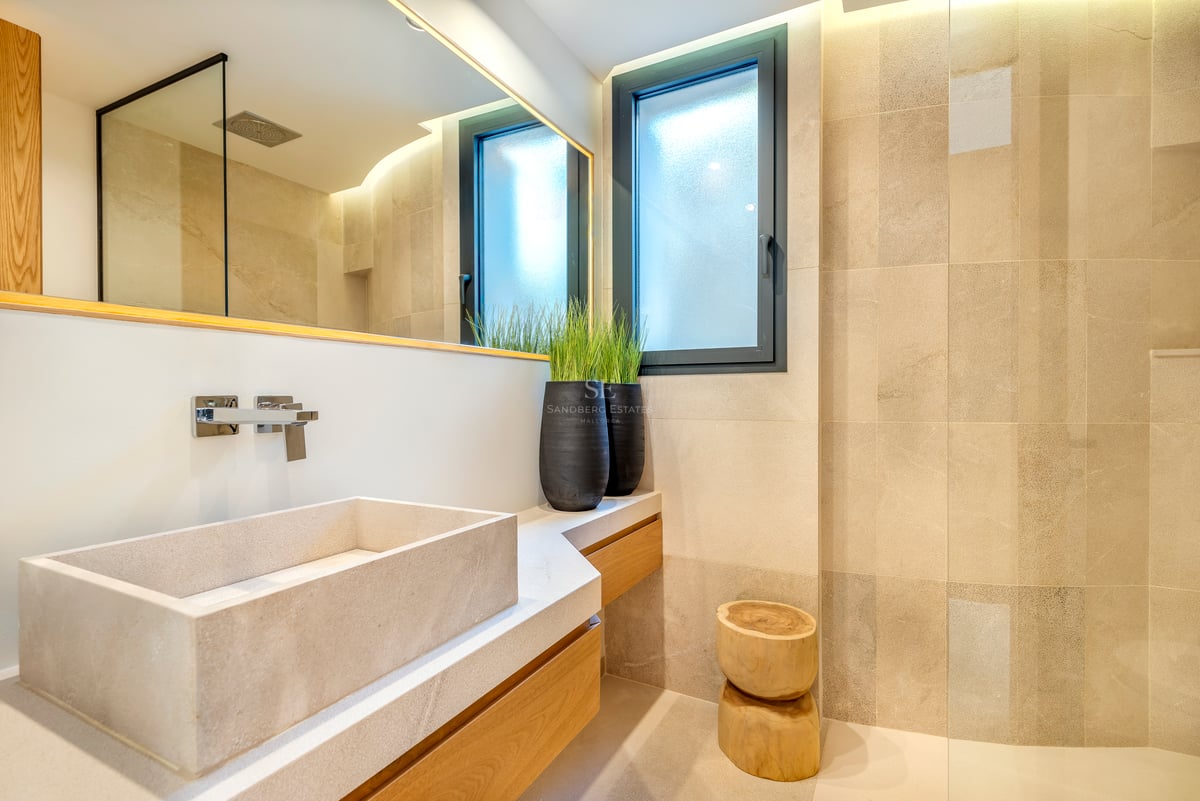 Salle de bains contemporaine avec vasque rectangulaire en pierre sur meuble en bois et éclairage tamisé.