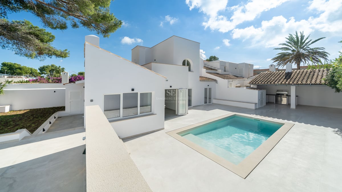 Villa méditerranéenne moderne blanche avec piscine étincelante, terrasse en pierre et cuisine extérieure.