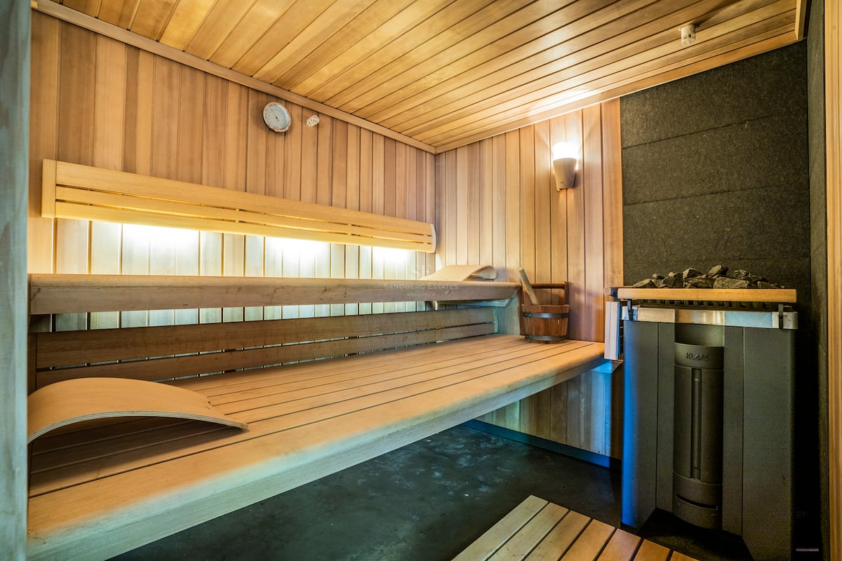 Innenansicht einer modernen Holzsauna mit mehrstufigen Bänken, Ambientebeleuchtung und KLAFS-Saunaofen.