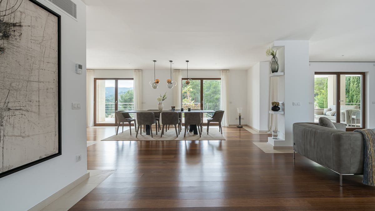 Salle à manger spacieuse avec parquet sombre, suspensions design et baies vitrées donnant sur un jardin verdoyant.