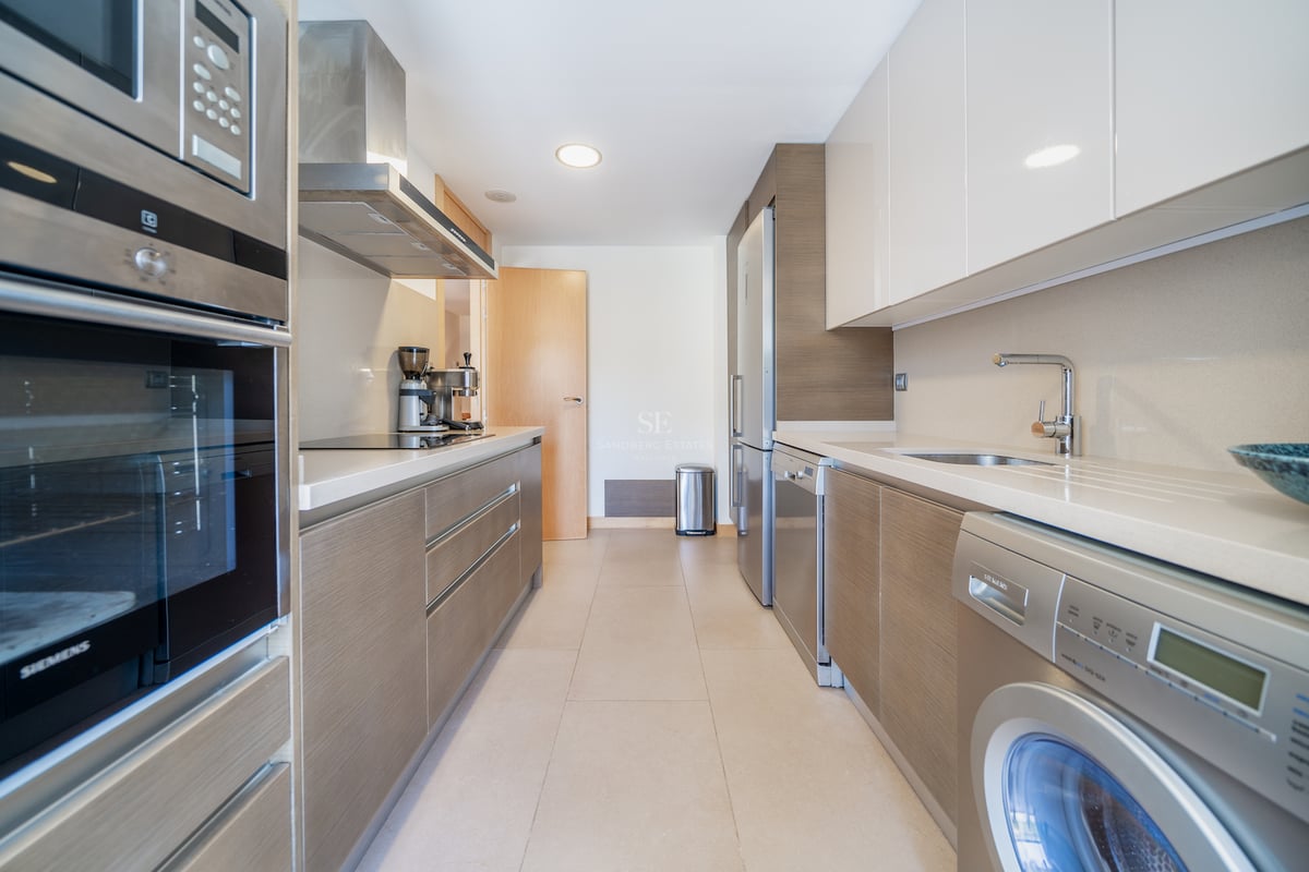 Cuisine en couloir avec meubles en bois et blanc, équipée d'appareils Siemens en acier inoxydable.