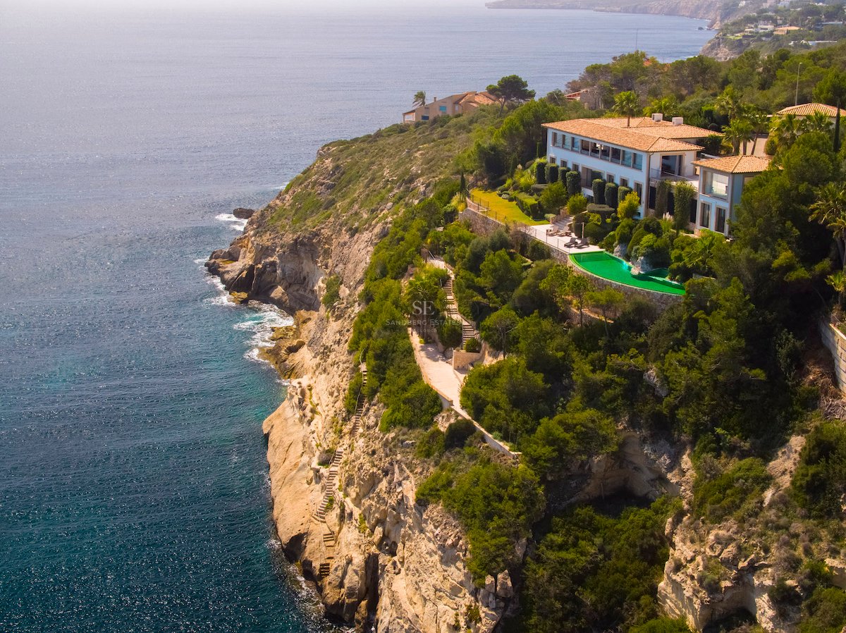 Luftaufnahme einer Luxusvilla in Klippenlage mit smaragdgrünem Pool und Panoramablick auf das Mittelmeer.