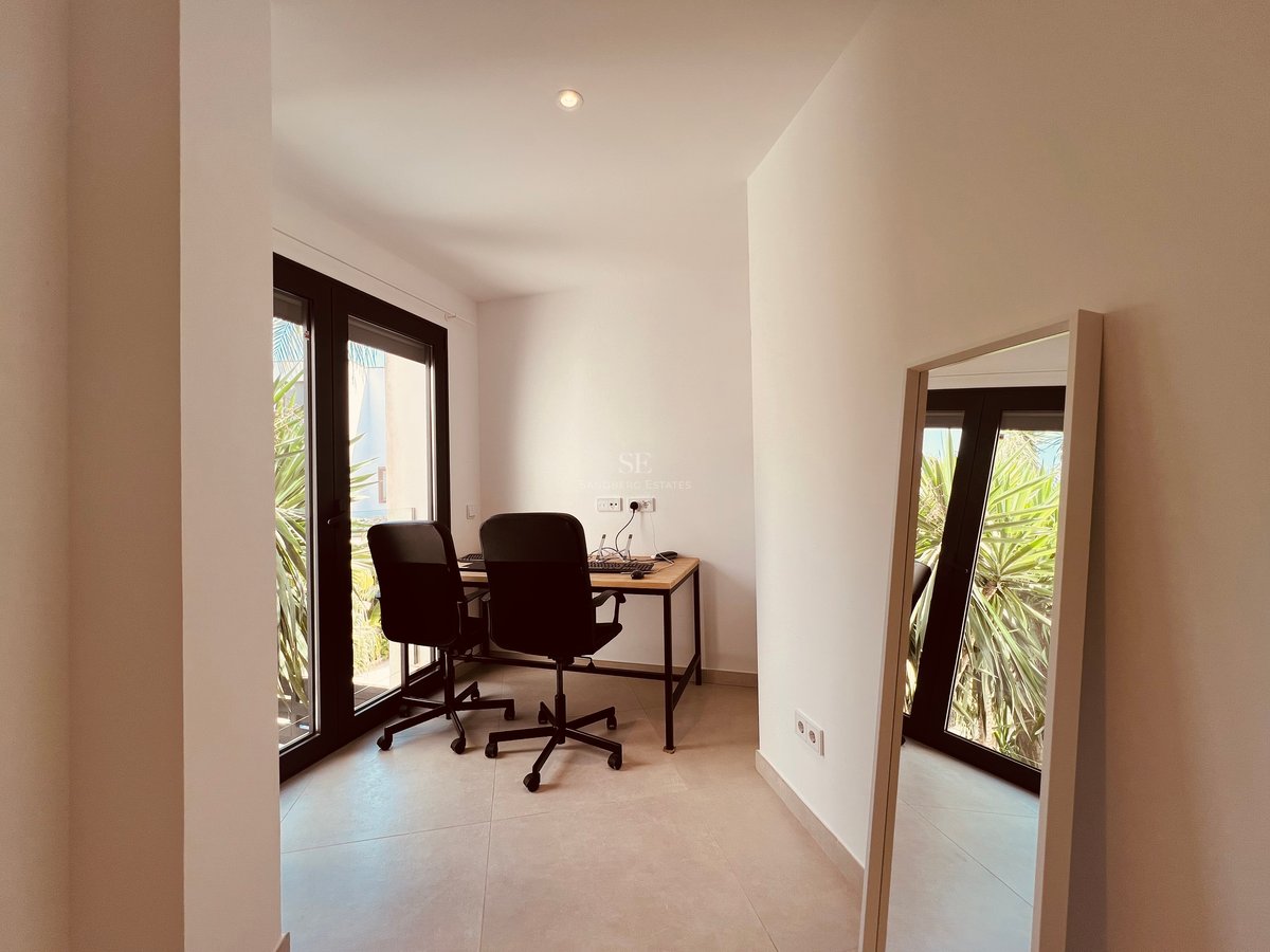 Bureau contemporain lumineux avec table en bois, chaises ergonomiques et grandes baies vitrées donnant sur le jardin.