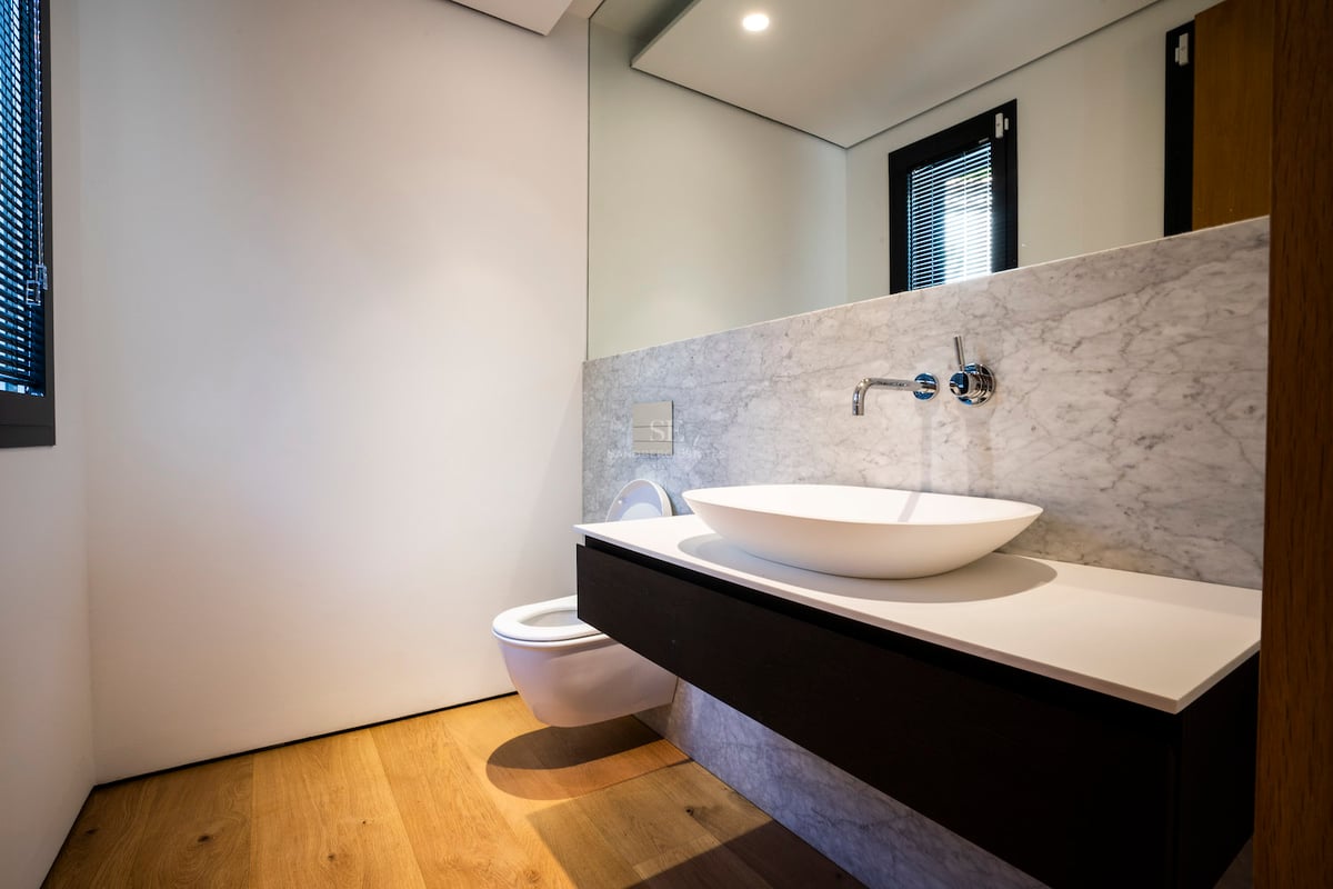 Zeitgenössisches Badezimmer mit Aufsatzwaschbecken auf schwebendem Waschtisch, Steinwänden und Holzboden.