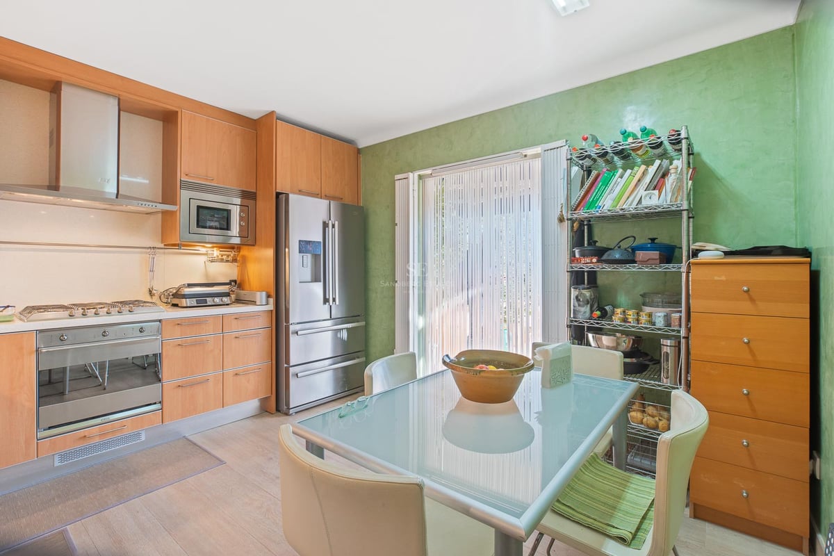 Zeitgenössische Küche mit hellen Holzfronten, Edelstahlgeräten und einem Esstisch aus Glas.