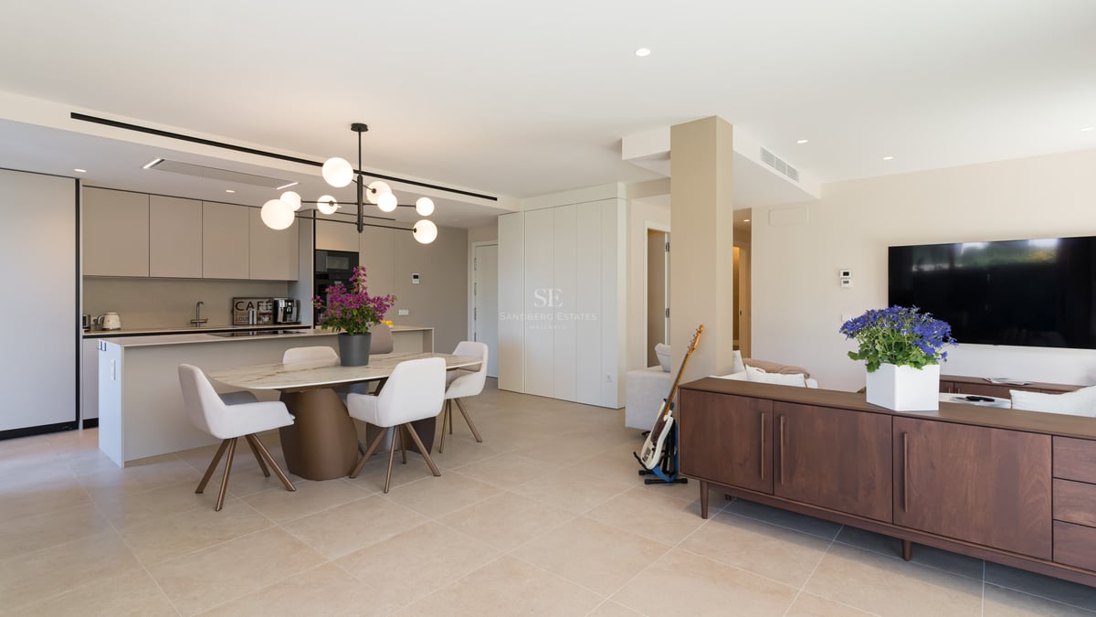 Bright open-concept room featuring a marble dining table, contemporary globe chandelier, and sleek integrated kitchen.
