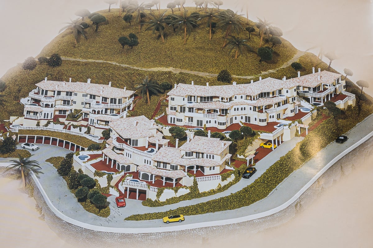 Spacious living room with large windows, light wood floors, modern furniture and views of the pool and lush garden.