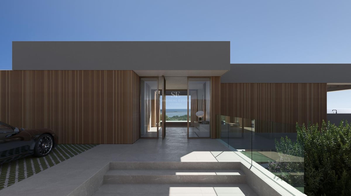 Entrée de villa minimaliste avec lattes de bois, portes pivotantes en verre et vue mer à travers le hall.
