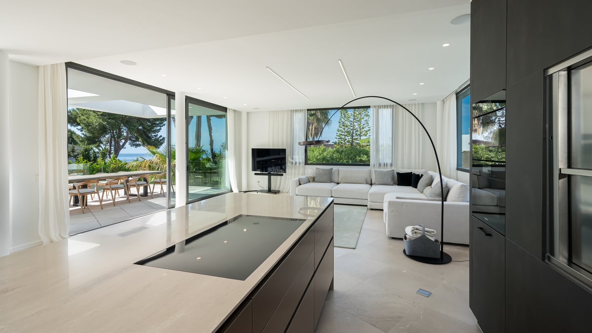 Salon contemporain et îlot de cuisine avec baies vitrées ouvrant sur une terrasse face à la Méditerranée.