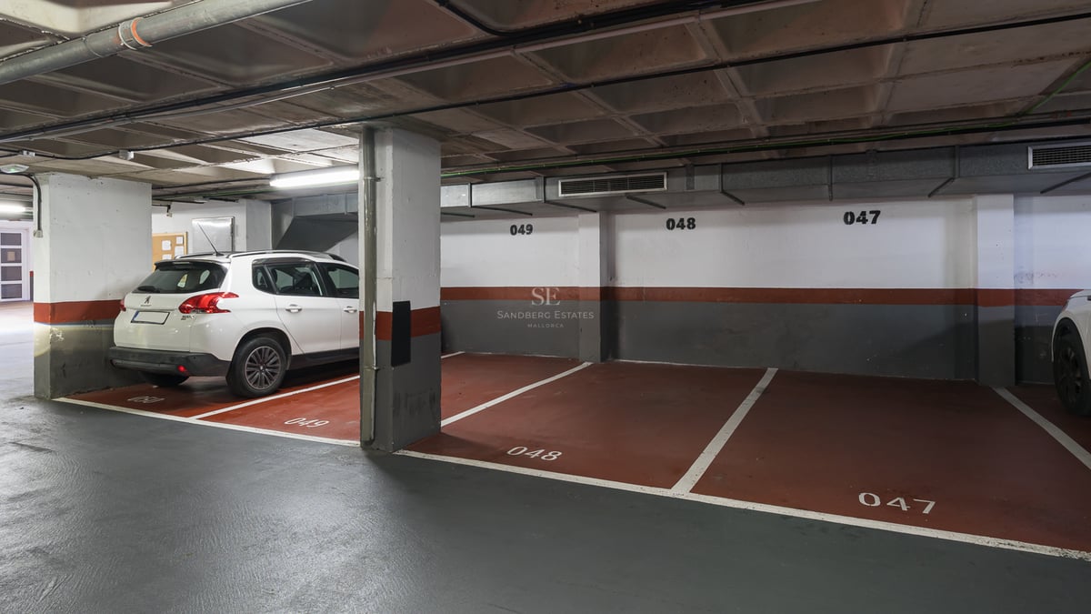 Inomhusgarage med numrerade platser och en vit SUV parkerad bredvid betongpelare.