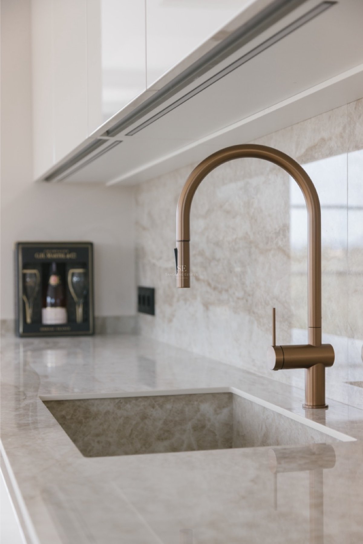 Nahaufnahme einer bronzenen Armatur auf einer Naturstein-Arbeitsplatte mit integriertem Spülbecken.