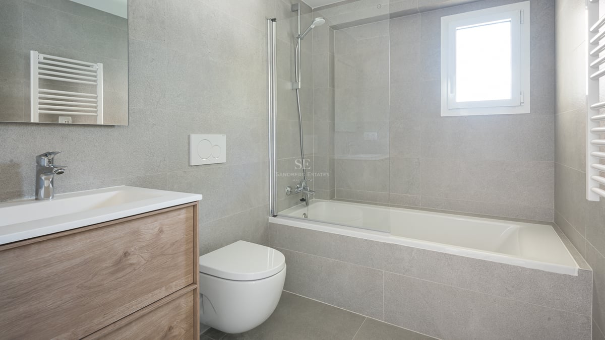 Salle de bain contemporaine avec carrelage gris effet pierre, baignoire et paroi en verre, et meuble sous vasque en chêne.