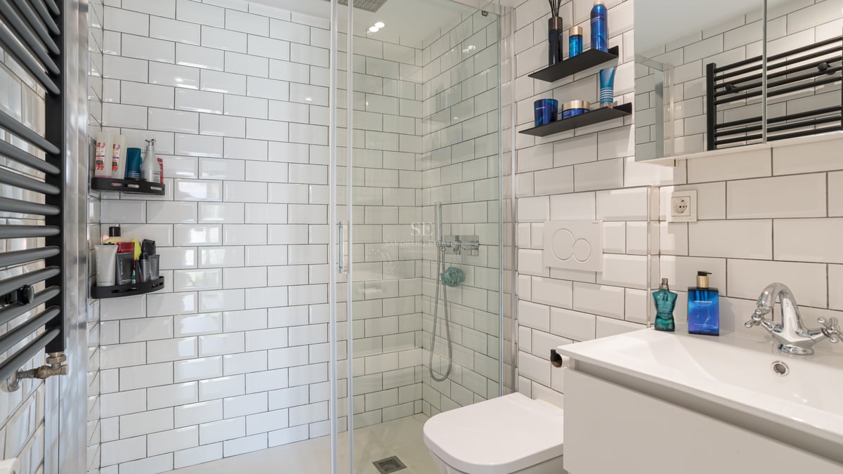 Salle de bains moderne avec carreaux de métro blancs, douche à l'italienne en verre et radiateur noir.