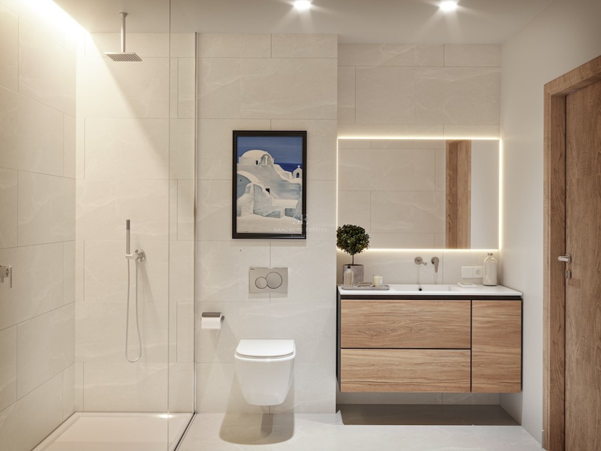 Modernt badrum med beige kakel, vägghängd kommod i trä, bakgrundsbelyst spegel och duschvägg i glas.