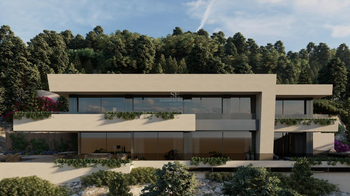 Vue de face d'une villa contemporaine à plusieurs niveaux avec de grandes baies vitrées et une façade couleur sable.