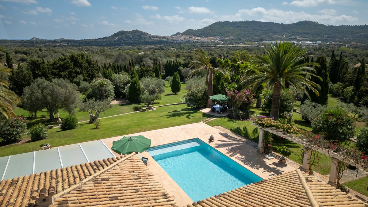 Vue surélevée d'une piscine rectangulaire entourée de terrasses en terre cuite et de jardins méditerranéens.