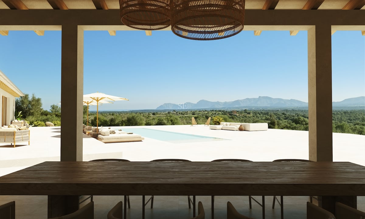 Une terrasse ombragée avec une table en bois sombre ouvrant sur une piscine et une chaîne de montagnes.