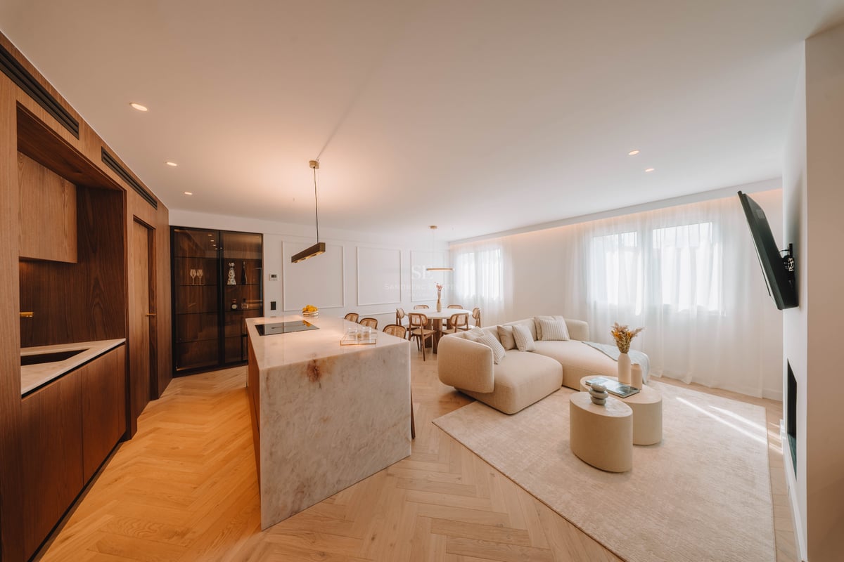 Salon à concept ouvert avec îlot en marbre, canapé beige et parquet en point de Hongrie.