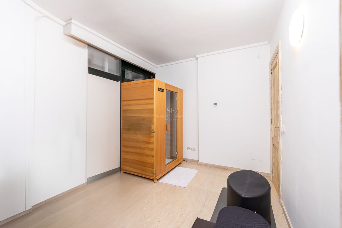 Pièce moderne blanche comprenant une cabine de sauna en bois autoportante et un sol en pierre claire.