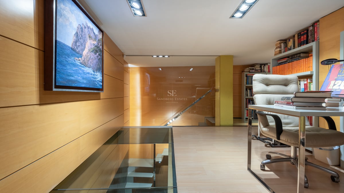 Bureau moderne avec sol en verre sur escalier, boiseries en bois clair et bibliothèques intégrées.