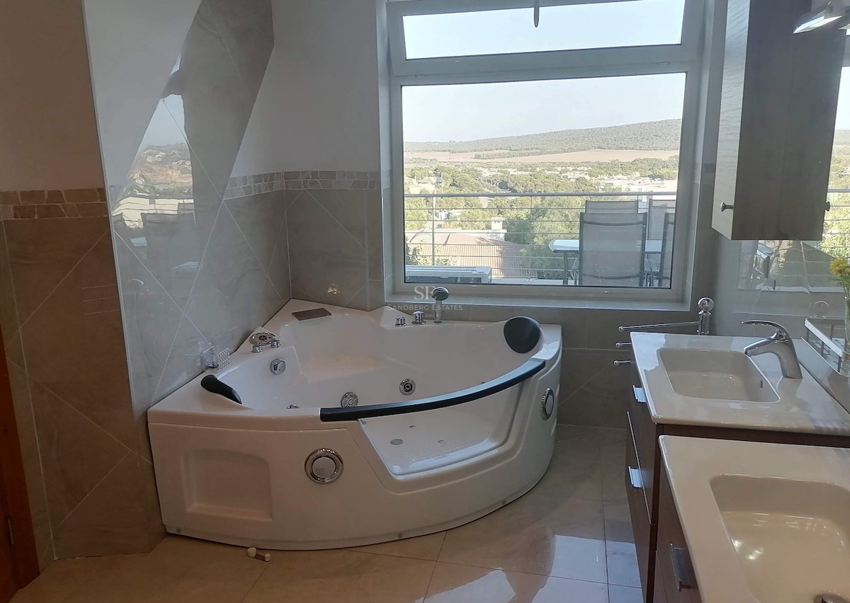 Salle de bains contemporaine avec baignoire balnéo d'angle, double vasque et vue sur la vallée verdoyante.