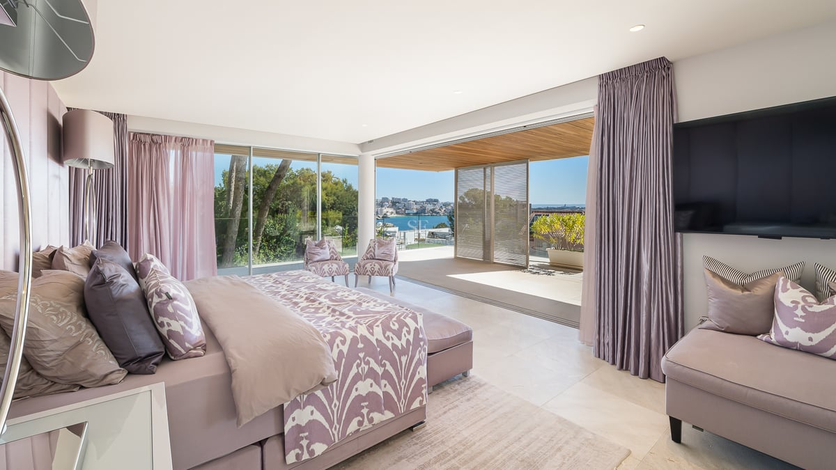 Helles Hauptschlafzimmer mit Doppelbett, zwei Sesseln und Zugang zur privaten Terrasse mit Blick auf die Küste.