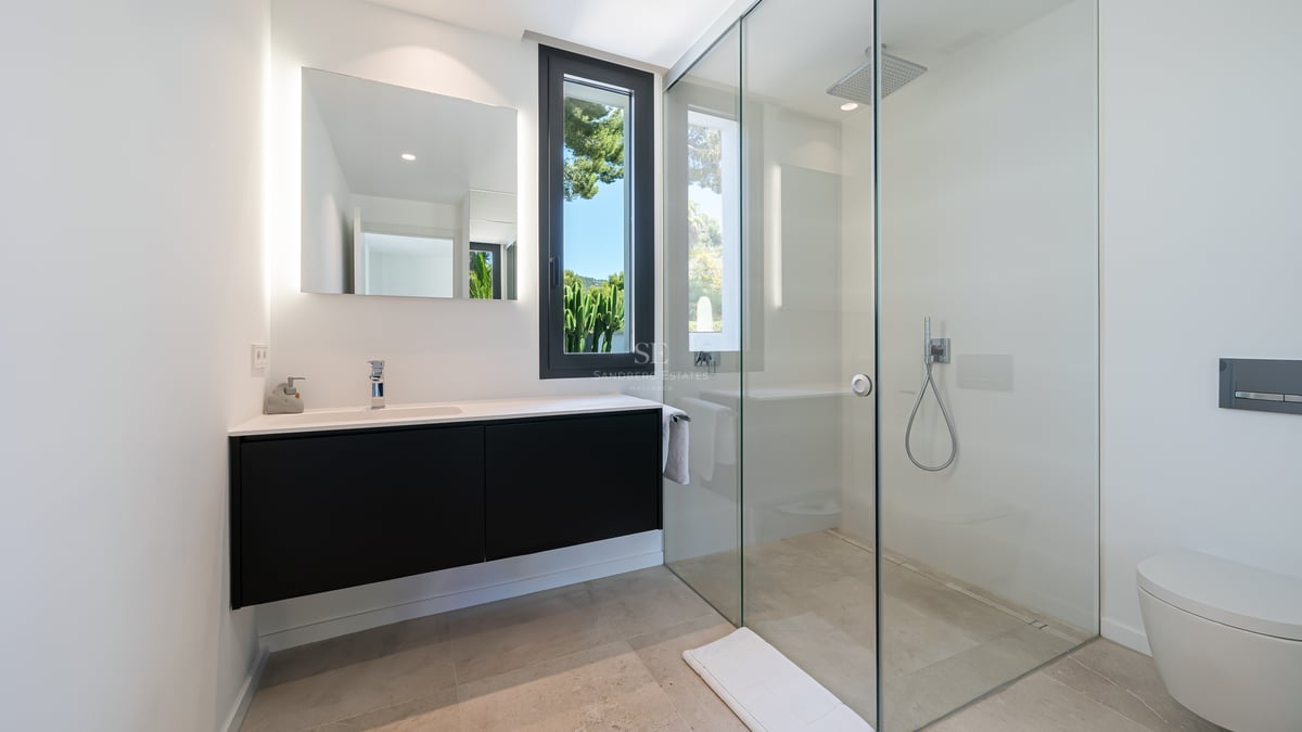 Salle de bains contemporaine avec douche à l'italienne en verre, meuble vasque noir et miroir rétroéclairé.
