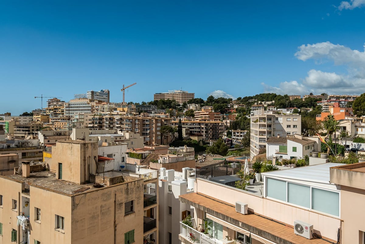 Weitwinkelblick auf die Skyline einer mediterranen Stadt mit Apartmenthäusern unter klarem blauem Himmel.