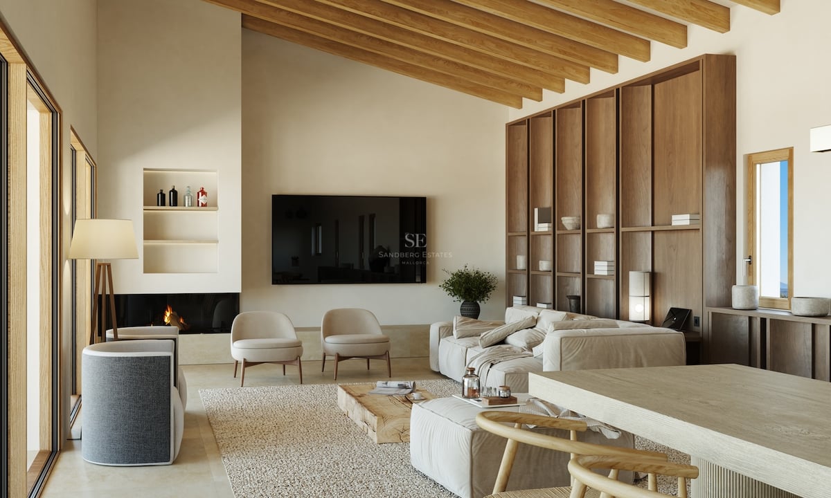 Salon spacieux avec de hauts plafonds à poutres apparentes, canapé en lin beige, bibliothèque en bois et cheminée.