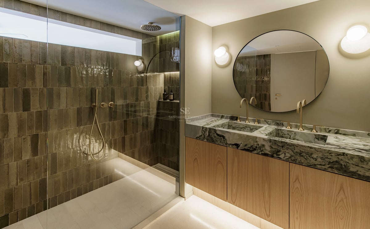 Modernes Badezimmer mit Glasdusche und Doppelwaschtisch aus Marmor mit goldenen Armaturen.