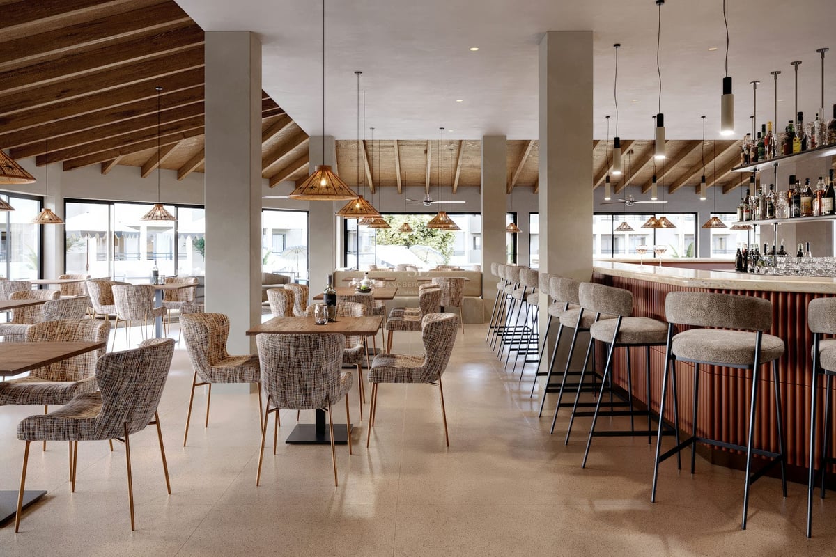Intérieur d'un salon moderne avec plafonds en bois, suspensions, tables à manger et un bar avec tabourets hauts.
