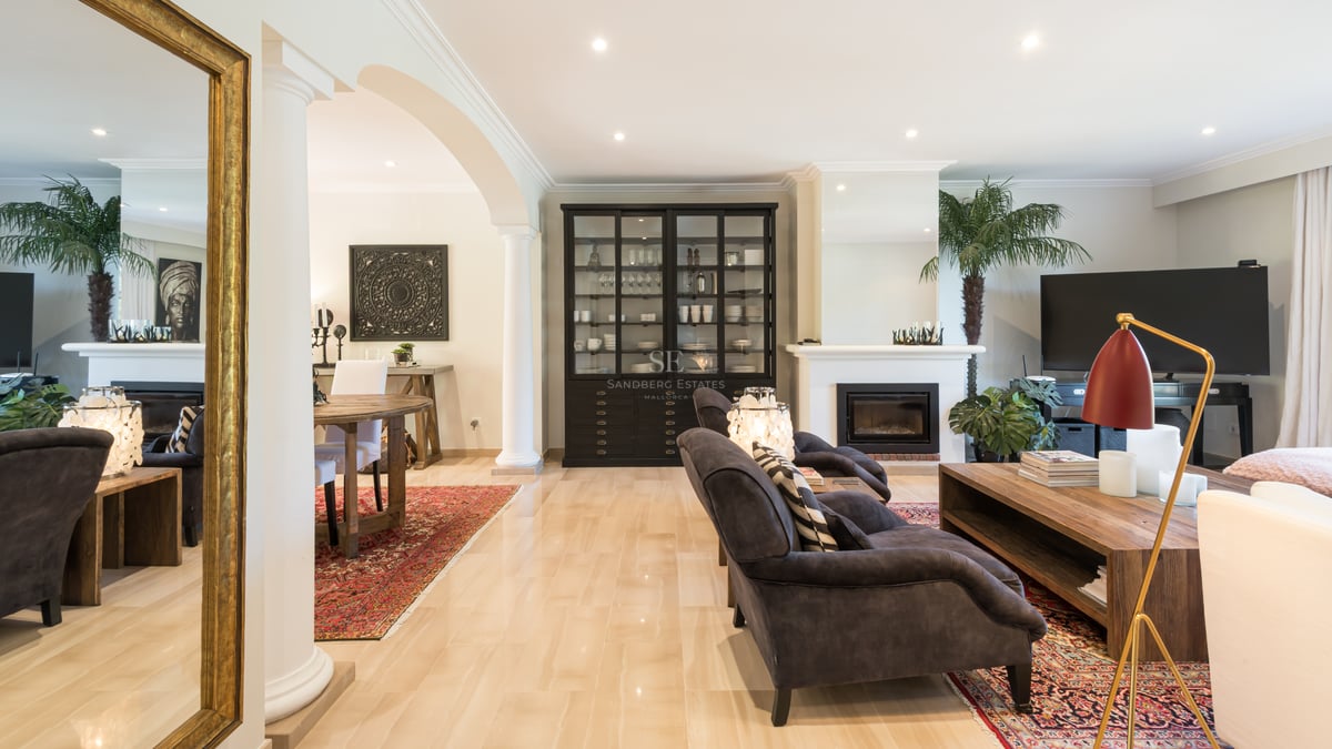 Spacious Mediterranean living room with marble floors, integrated fireplace, classical arches, and luxury furnishings.