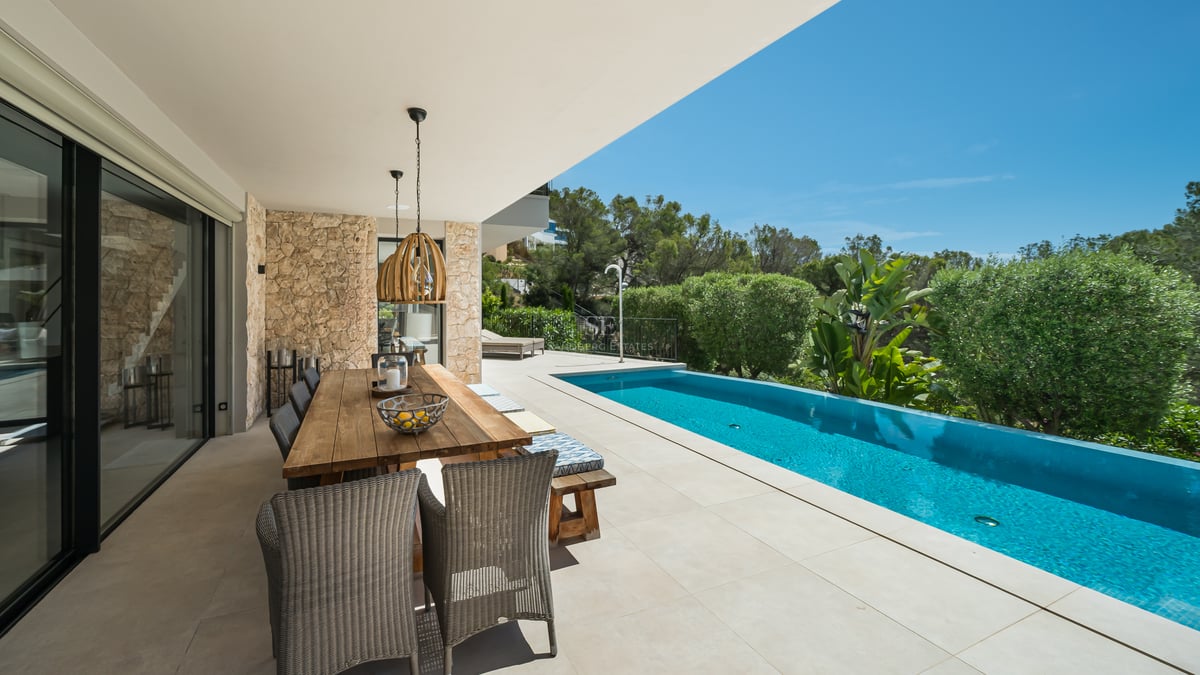 Grand balcon avec vue panoramique sur la mer. Mobilier moderne, garde-corps en verre et plancher en bois. Design élégant et lumineux.