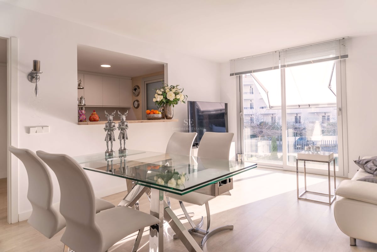 Zeitgenössischer Essbereich mit Glastisch, weißen Lederstühlen und großen Schiebetüren zur Terrasse.