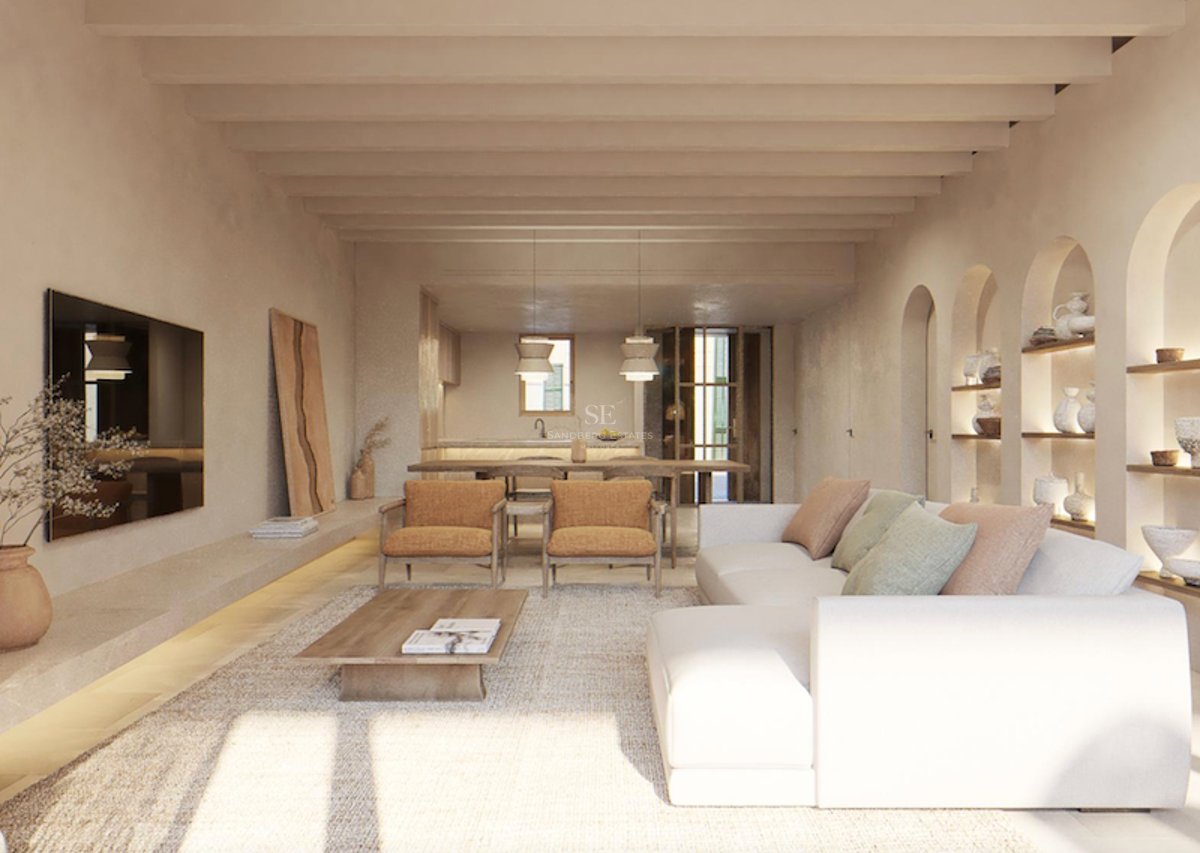 Salon lumineux avec canapé blanc, poutres en bois au plafond et niches murales cintrées exposant des céramiques.