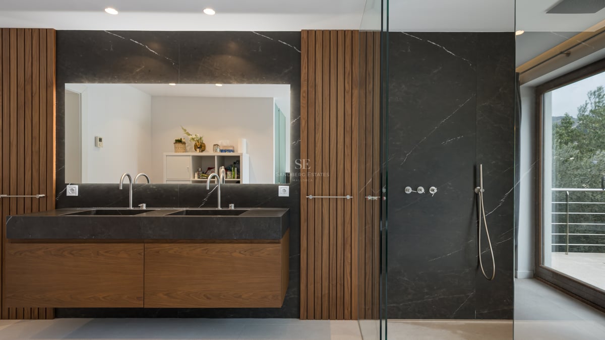 Salle de bains moderne avec double vasque en marbre noir, boiseries en noyer et douche à l'italienne vitrée.