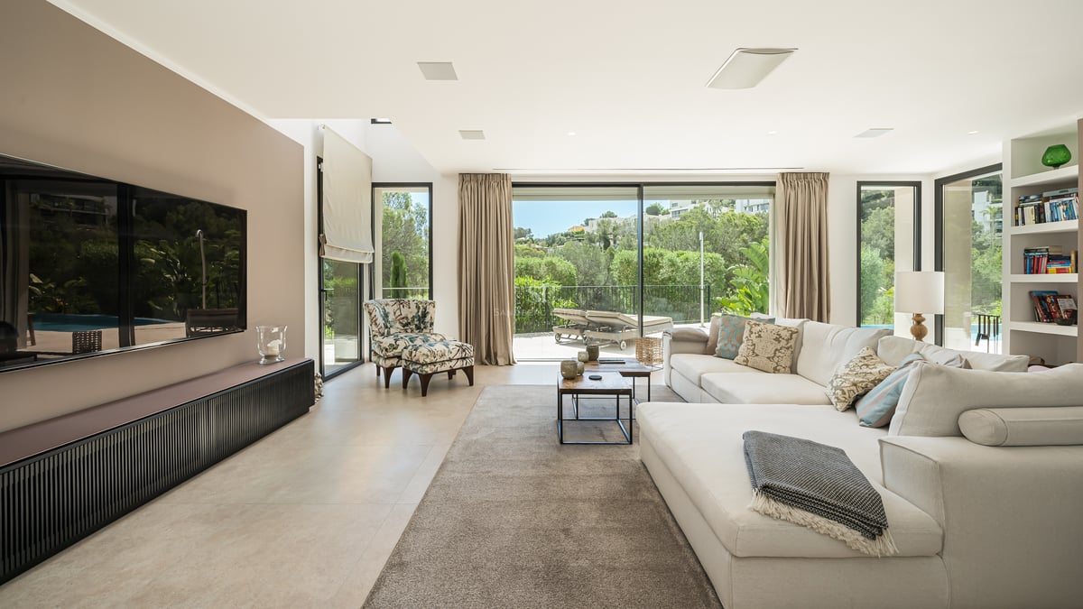 Vaste salon avec baies vitrées, parquet clair et mobilier design minimaliste. Vue sur piscine et jardin luxuriant.