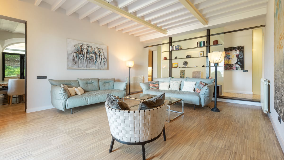 Rymligt modernt vardagsrum med ljusblå soffor, designfåtölj och vita takbjälkar.