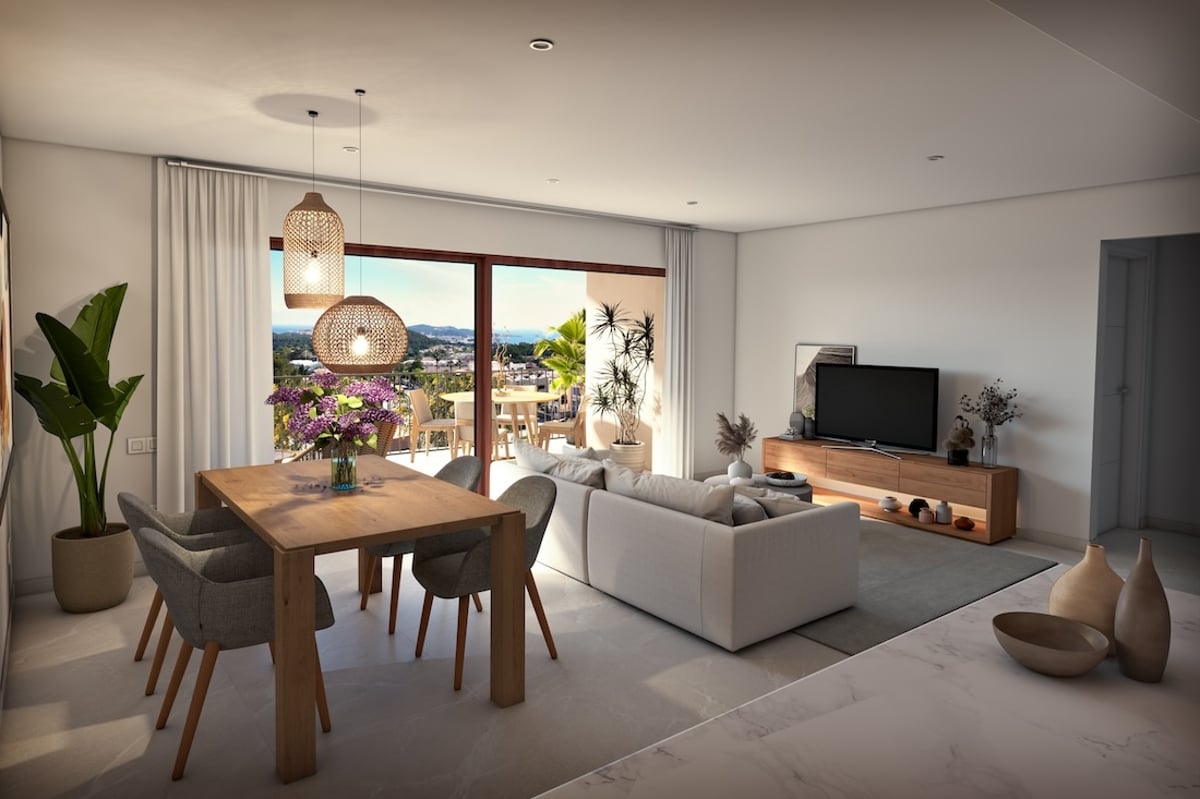 Bright open-concept living and dining area with wooden furniture and large windows overlooking a scenic coastline.