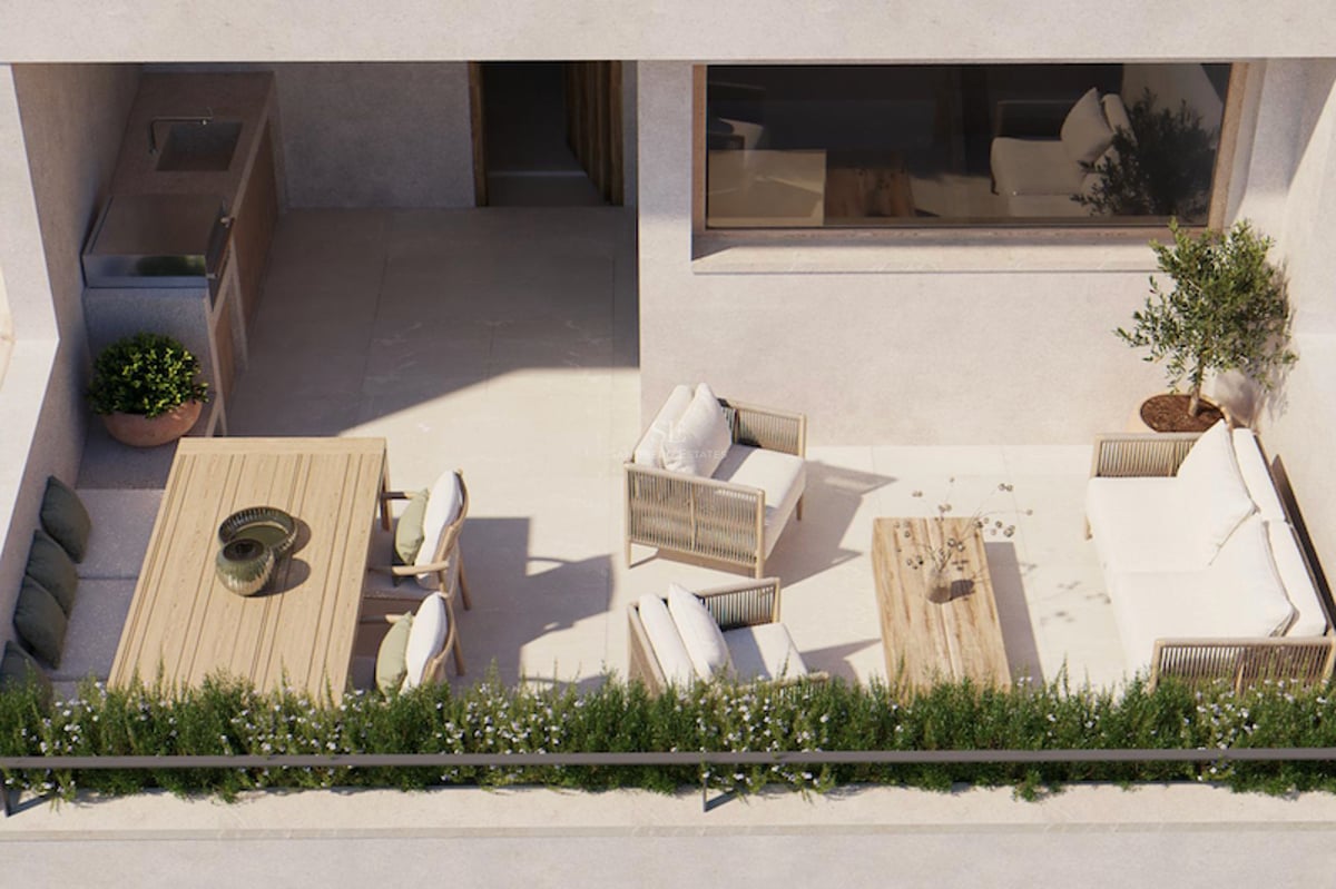 Vue plongeante d'une terrasse moderne ensoleillée comprenant un salon, une table à manger et une cuisine d'été avec grill.