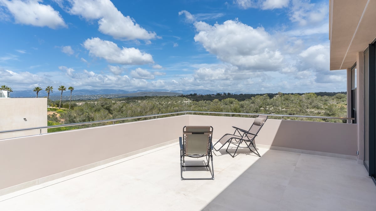 Minimalistische Dachterrasse mit zwei Sonnenliegen und weitem Blick über grüne Täler und ferne Berge.