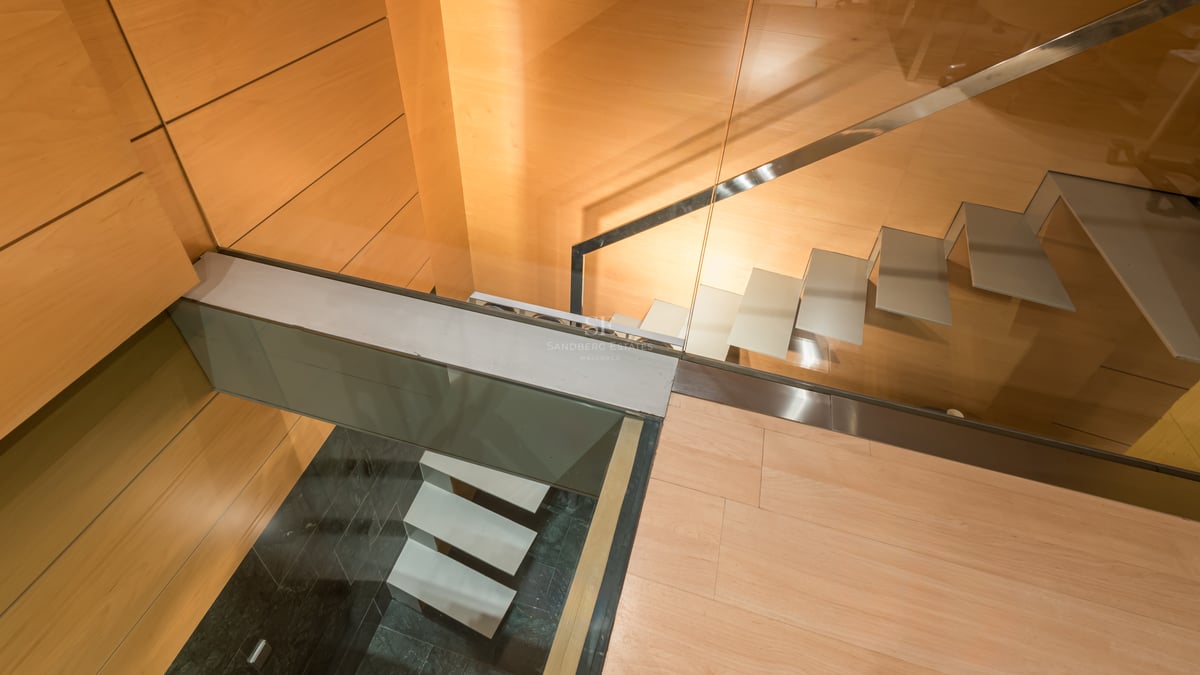 Vue plongeante d'un escalier moderne avec marches en verre et parois en bois chaleureux.