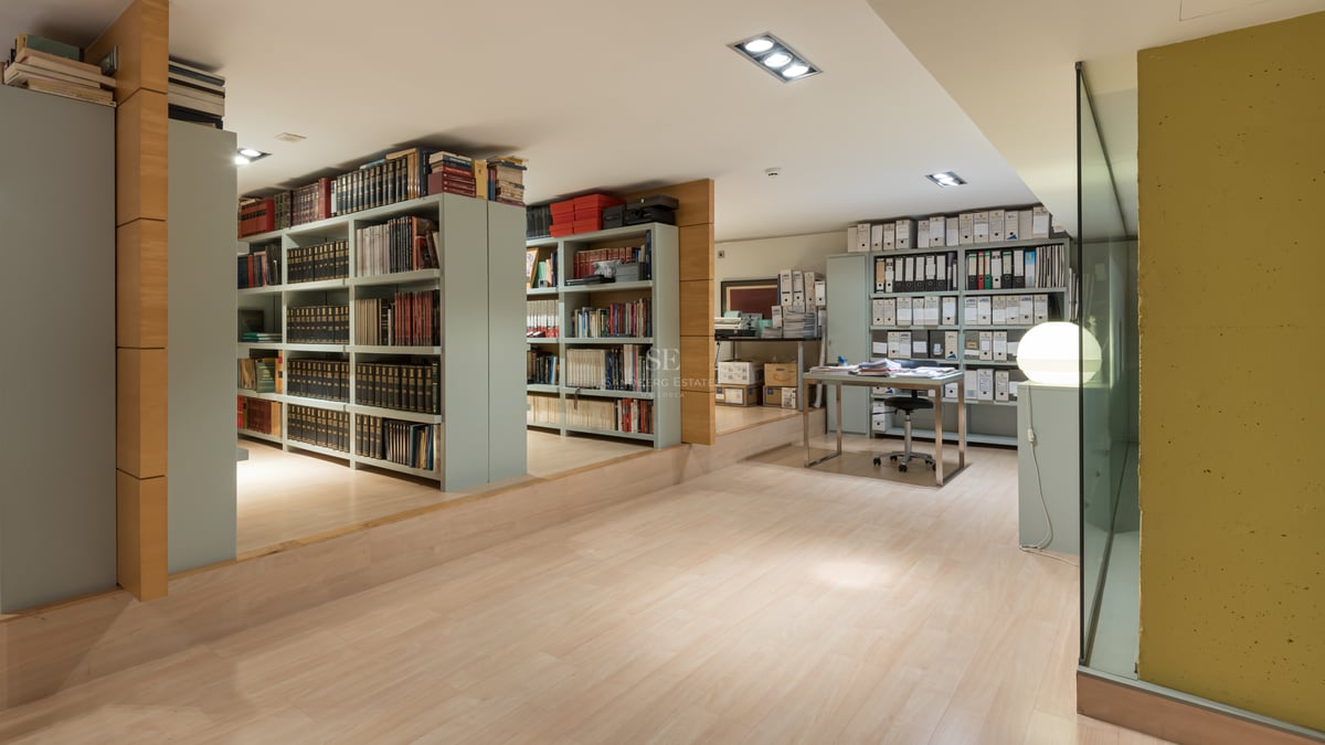 Grand bureau à domicile avec vastes rayonnages, parquet clair et bureau moderne en verre.