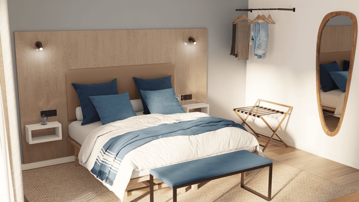 Une chambre moderne avec tête de lit en bois, oreillers bleus, banc bleu et miroir ovale sous une lumière naturelle.